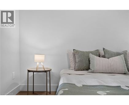 A bedroom with a bed, a lamp, and a wall with a REALTOR® logo.
