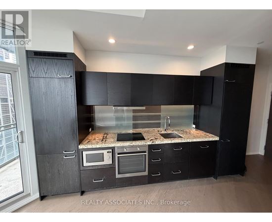 A modern kitchen with black cabinets and a granite countertop.