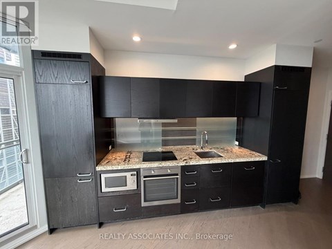 A modern kitchen with black cabinets and a granite countertop.