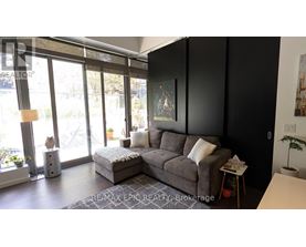 A living room with a grey sofa and a large window.