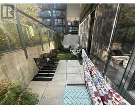 A patio with a table and chairs is surrounded by a concrete wall and glass doors.
