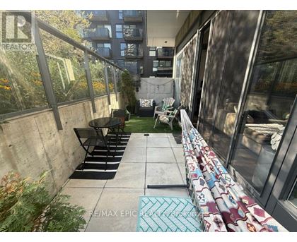 A patio with a table and chairs is surrounded by a concrete wall and glass doors.