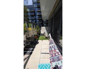 A balcony with a table and chairs overlooks a grassy area.