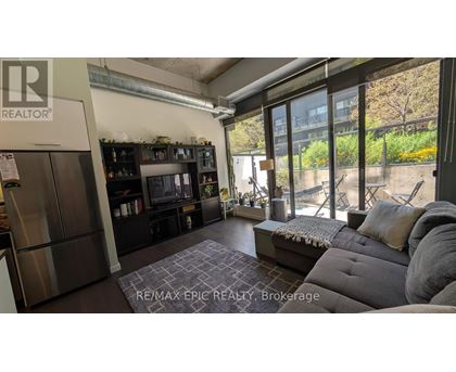 A living room with a grey couch and a large window.
