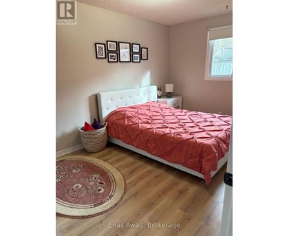 A bedroom with a bed covered in a red comforter and a white headboard.