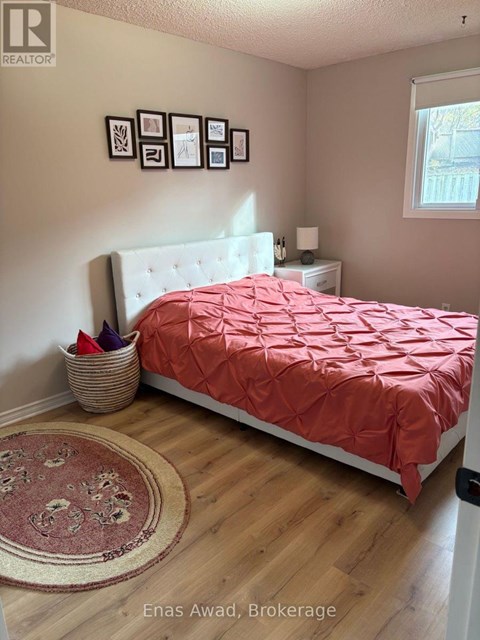 A bedroom with a bed covered in a red comforter and a white headboard.
