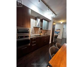 A kitchen with dark wood cabinets and a brick backsplash.