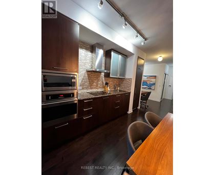 A kitchen with dark wood cabinets and a brick backsplash.