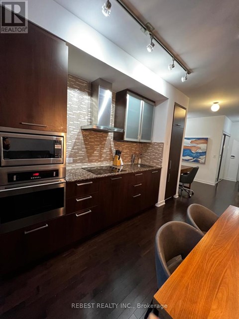 A kitchen with dark wood cabinets and a brick backsplash.
