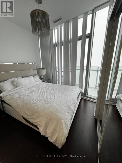 A bedroom with a large bed and a chandelier.