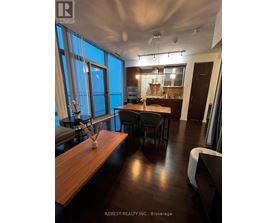 A modern dining room with a long wooden table and chairs.