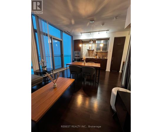 A modern dining room with a long wooden table and chairs.