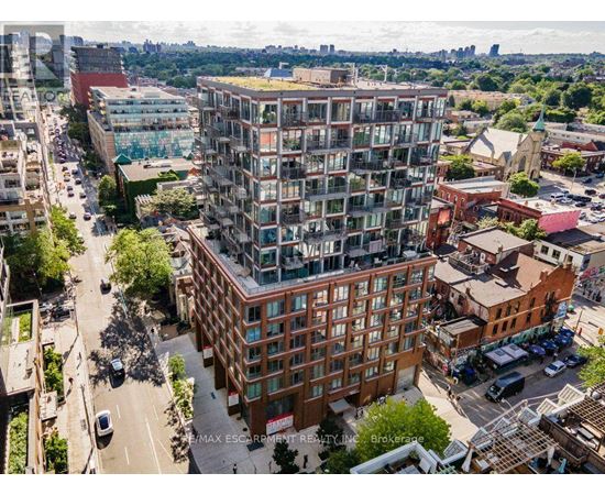 A tall building with a green roof is in the center of a city street.