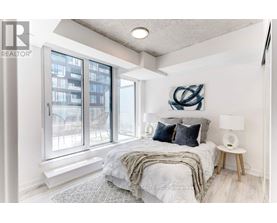 A bedroom with a large bed and a view of a building outside the window.