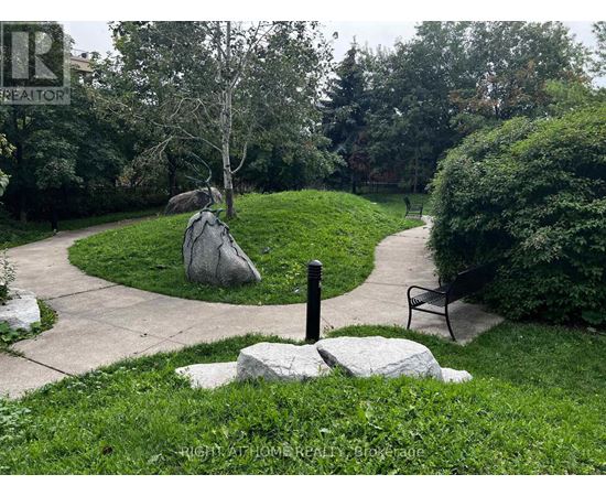 A park with a bench and a stone with a post on it.