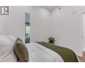 A bedroom with a bed, a side table, and a plant.