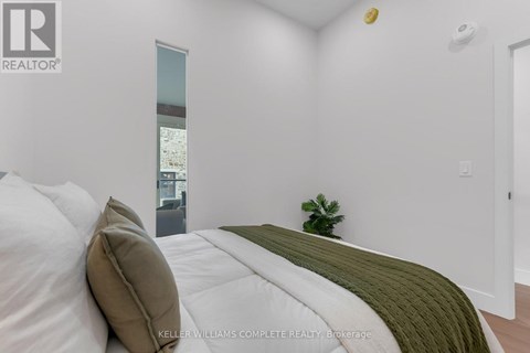 A bedroom with a bed, a side table, and a plant.