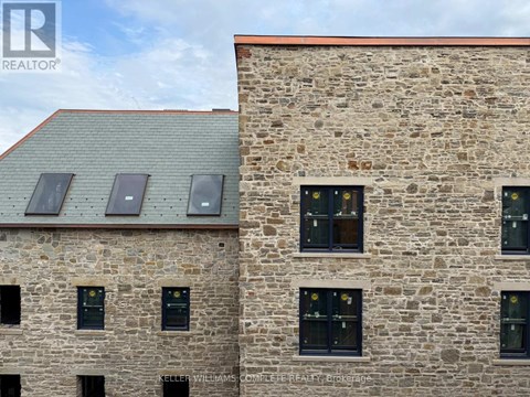 A stone building with windows and a metal roof.