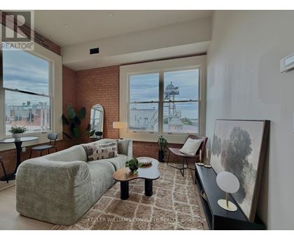 A living room with a grey couch, a brown rug, and a painting on the wall.
