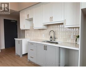 A kitchen with white cabinets and a black door.