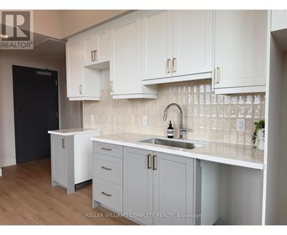 A kitchen with white cabinets and a black door.
