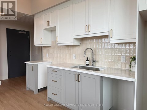 A kitchen with white cabinets and a black door.