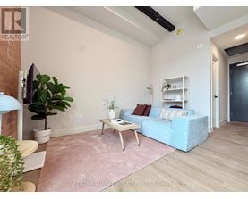 A living room with a blue couch, a wooden coffee table, and a pink rug.