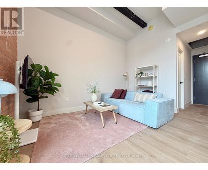 A living room with a blue couch, a wooden coffee table, and a pink rug.