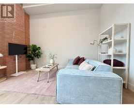 A living room with a blue couch, a white shelf, and a flat screen TV mounted on a brick wall.