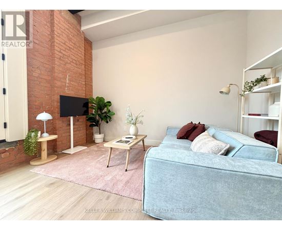 A living room with a blue couch and a brick wall.