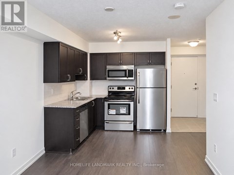 A kitchen with a refrigerator, oven, microwave, and sink.