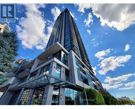 A tall, modern building with a glass facade and a unique design stands under a blue sky with clouds.