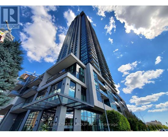 A tall, modern building with a glass facade and a unique design stands under a blue sky with clouds.