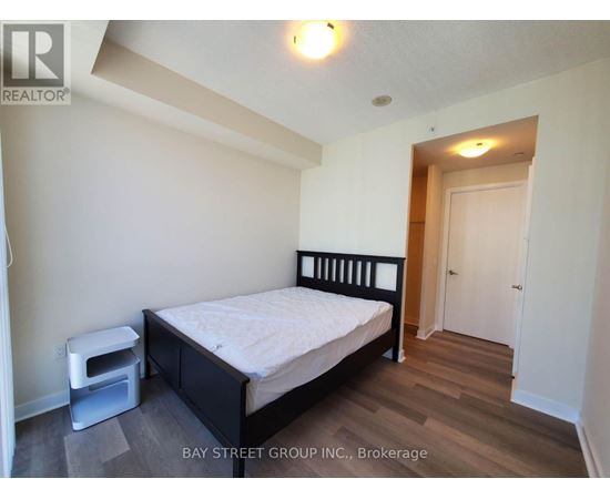 A bedroom with a bed, nightstand, and a wood floor.