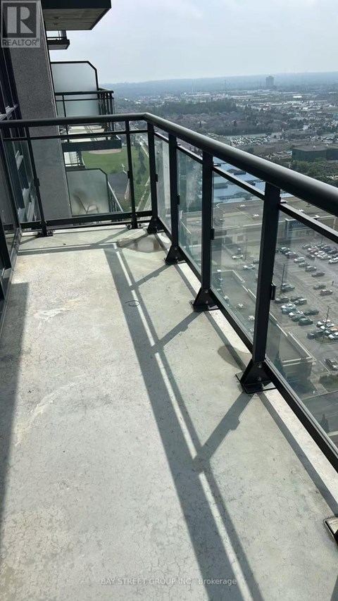 A balcony with a glass railing overlooking a cityscape.