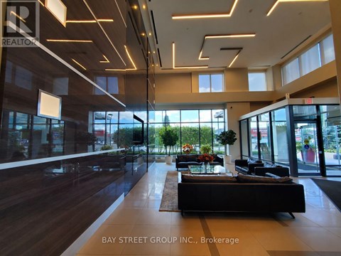 A modern office space with a long black couch and a large window.