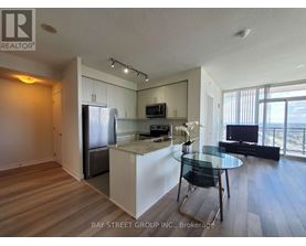 A kitchen with a refrigerator, microwave, and a dining table with chairs.