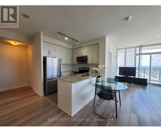 A kitchen with a refrigerator, microwave, and a dining table with chairs.
