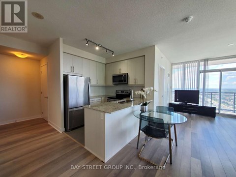 A kitchen with a refrigerator, microwave, and a dining table with chairs.
