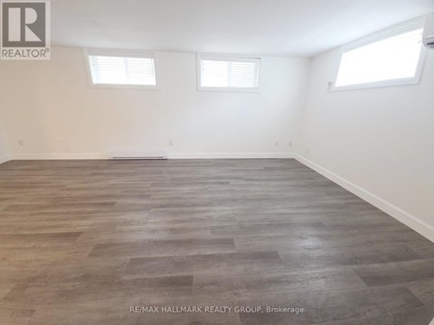 A room with wooden flooring and two windows.