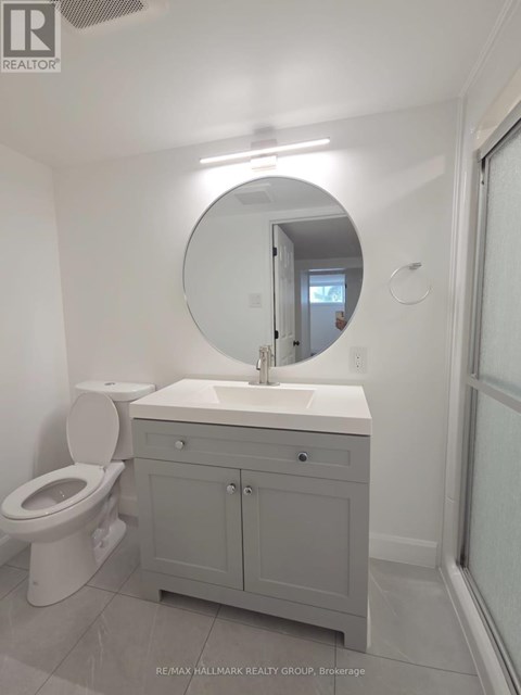 A white bathroom with a toilet, sink and mirror.