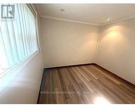 A room with wooden flooring and a window with blinds.