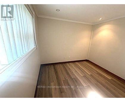 A room with wooden flooring and a window with blinds.