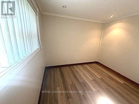 A room with wooden flooring and a window with blinds.