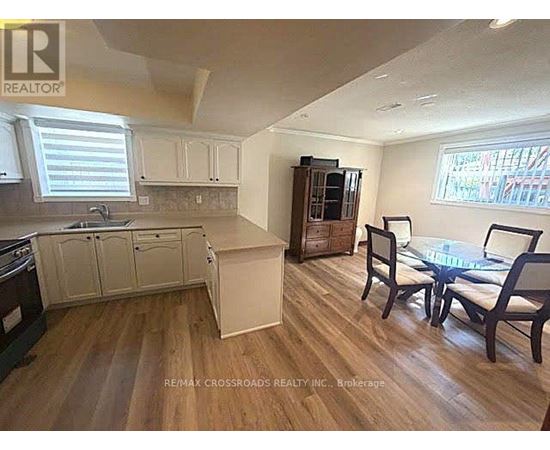 A kitchen with a table and chairs in the foreground and a cabinet with a microwave in the background.
