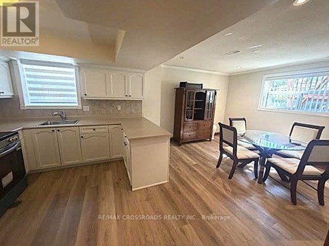 A kitchen with a table and chairs in the foreground and a cabinet with a microwave in the background.