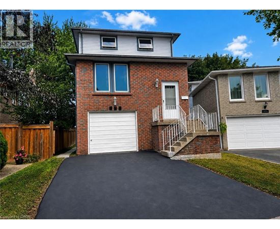 A house with a grey roof and a brick chimney has a white garage door.