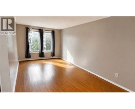 A room with a wooden floor and a window with black curtains.