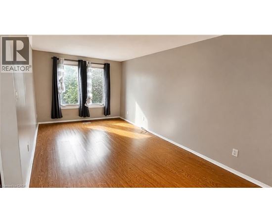 A room with a wooden floor and a window with black curtains.