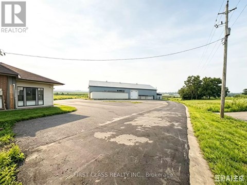 A road leading to a building with a sign that says "First Class Realty Inc. Brokerage".